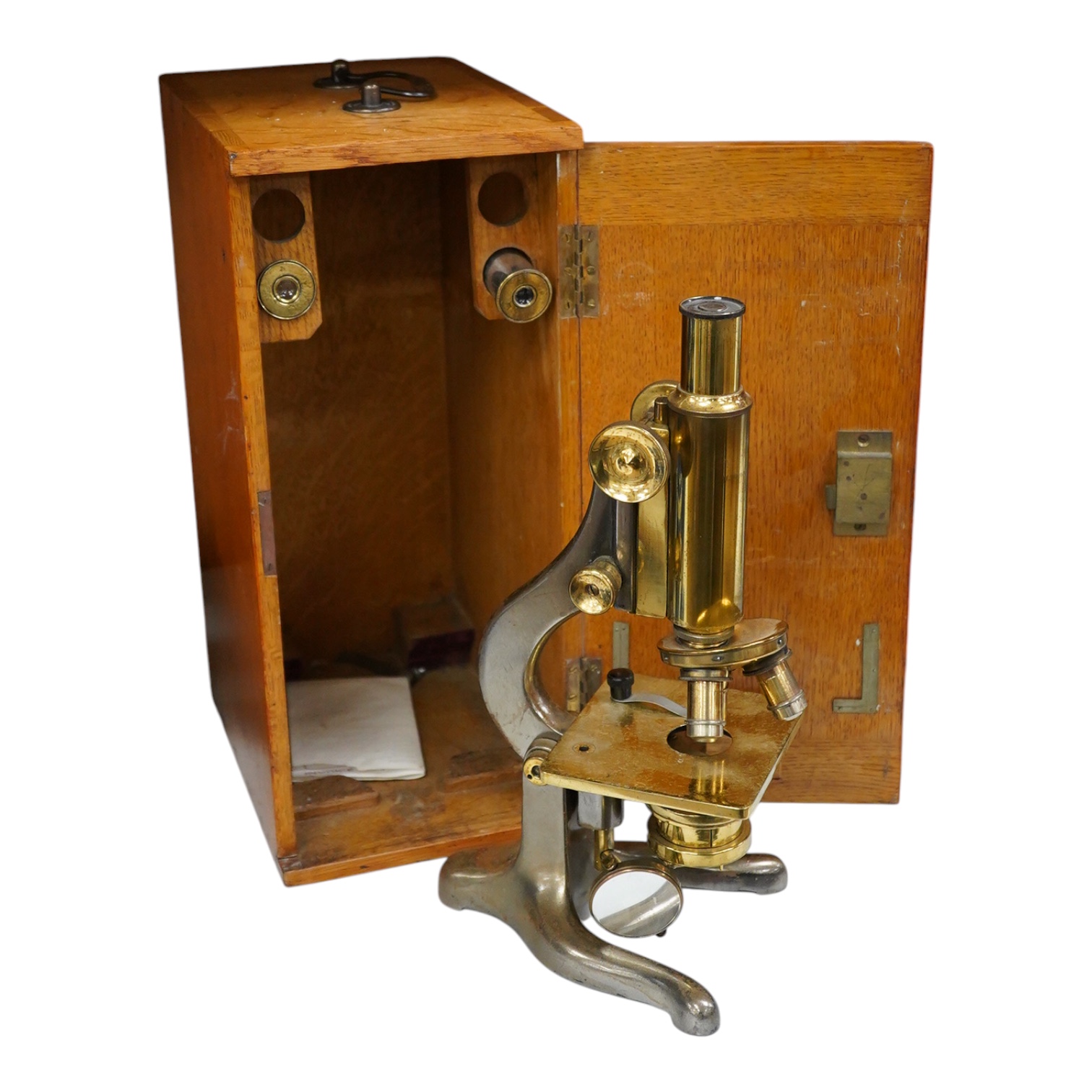 An early 20th century oak cased brass ‘Kima’ microscope by W. Watson & Sons Ltd. London, with engraved serial number under the maker’s name; 53622, with two alternative lenses in fitted compartments, microscope approxima